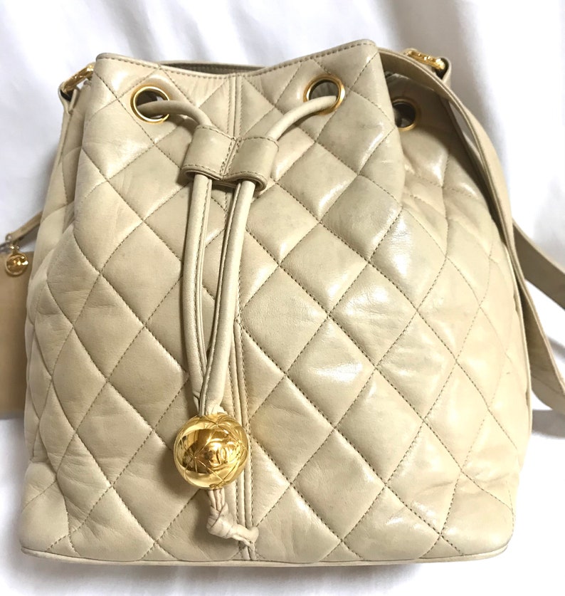 Luxury Chanel Vintage beige quilted lamb leather hobo bucket shoulder bag with drawstrings and golden CC mark ball
